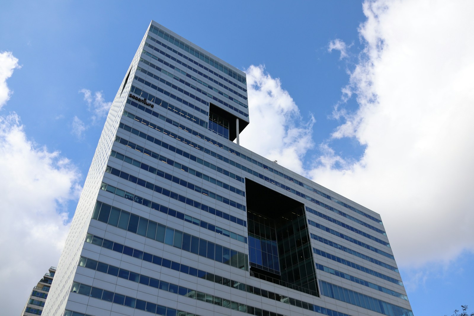 A modern office tower seen from below against a blue sky.