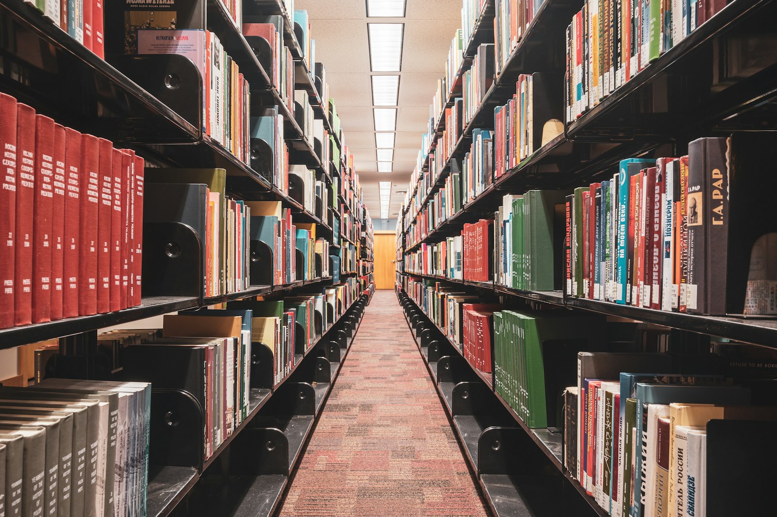 A long aisle between shelves filled with books in a library.